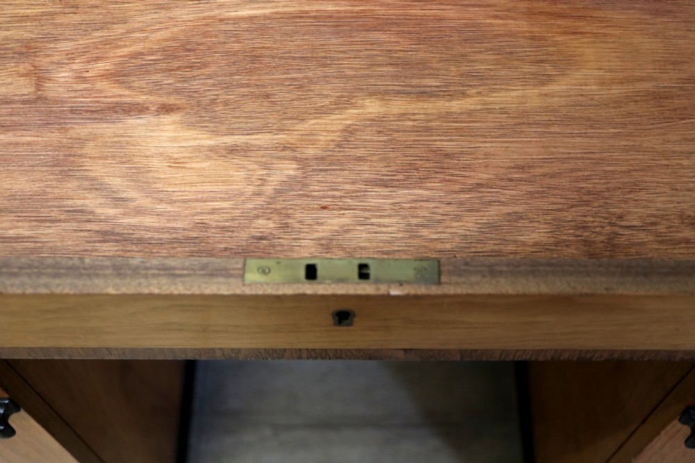 An Art Deco walnut pedestal desk featuring a glass-topped centre writing surface and hinged fold-out side flaps supported by twin cabinet bases. View XXIV