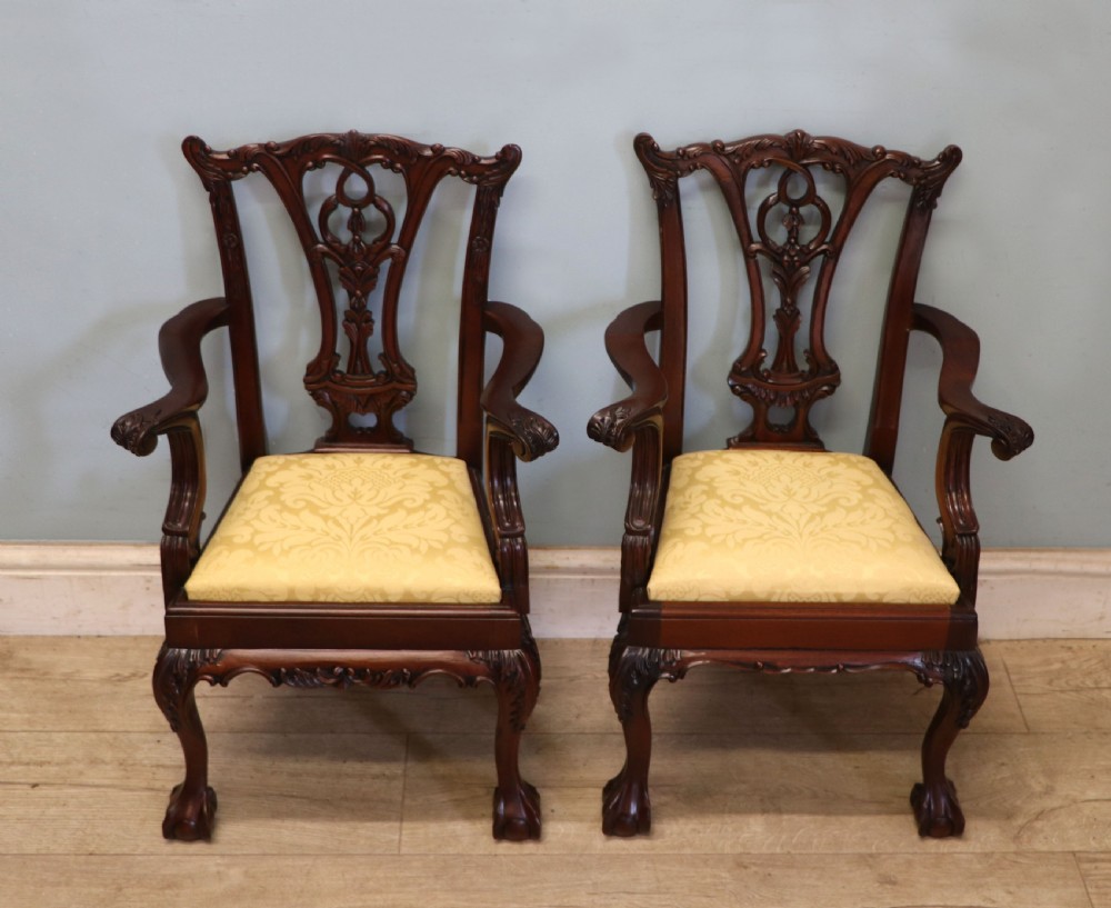 A pair of Georgian revival style child carver chairs made of polished dark mahogany with pierced splat backs, cabriole legs, ball and claw feet, and yellow damask upholstered seats.