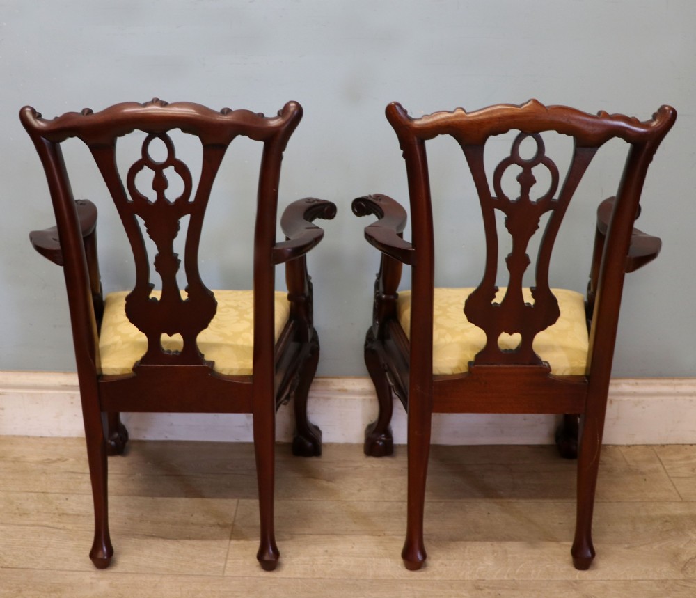 A pair of Georgian revival style child carver chairs made of polished dark mahogany with pierced splat backs, cabriole legs, ball and claw feet, and yellow damask upholstered seats. View V