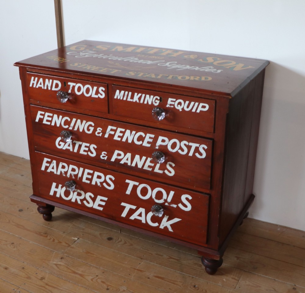 A Victorian red painted pine chest of four drawers featuring white, yellow, and green hand-painted commercial sign-writing and cut glass knobs. View V