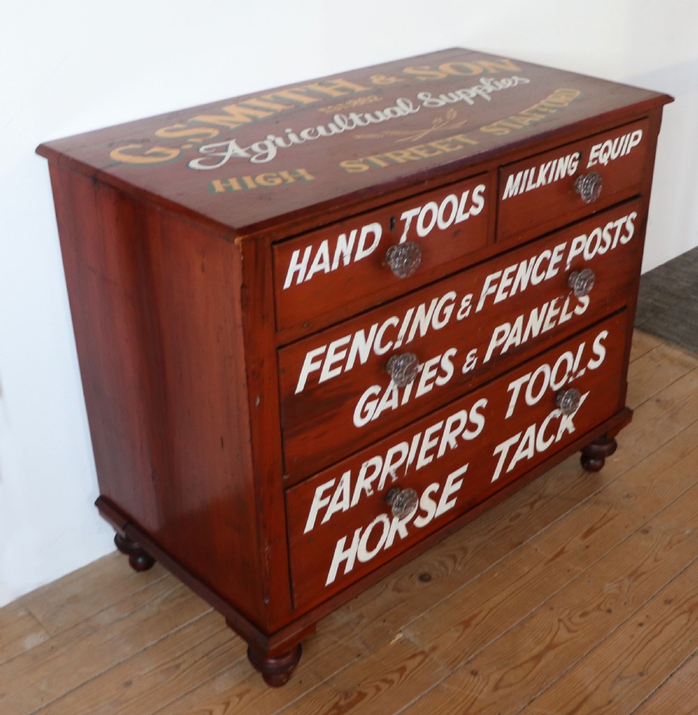 A Victorian red painted pine chest of four drawers featuring white, yellow, and green hand-painted commercial sign-writing and cut glass knobs. View VI