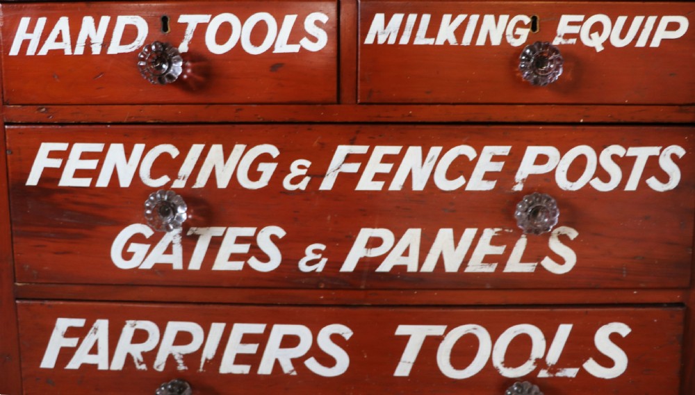 A Victorian red painted pine chest of four drawers featuring white, yellow, and green hand-painted commercial sign-writing and cut glass knobs. View XVI