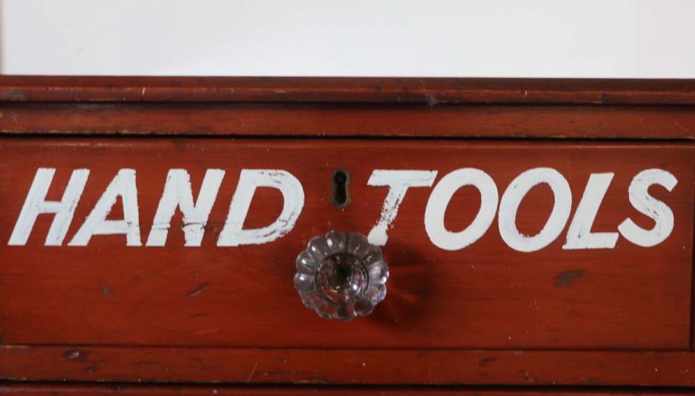 A Victorian red painted pine chest of four drawers featuring white, yellow, and green hand-painted commercial sign-writing and cut glass knobs. View XVII
