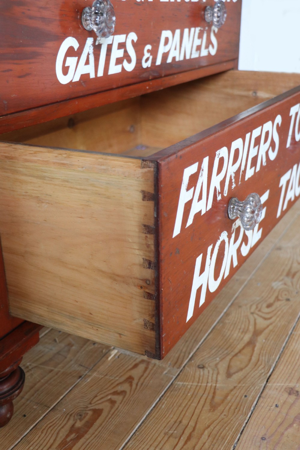A Victorian red painted pine chest of four drawers featuring white, yellow, and green hand-painted commercial sign-writing and cut glass knobs. View XXIII