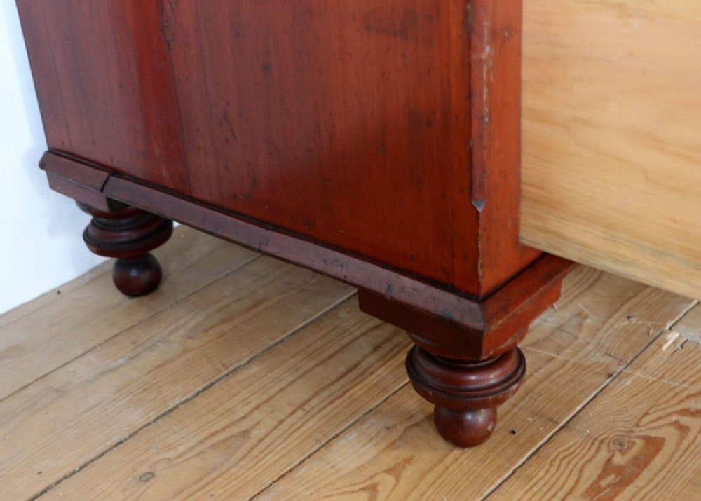 A Victorian red painted pine chest of four drawers featuring white, yellow, and green hand-painted commercial sign-writing and cut glass knobs. View XXVI