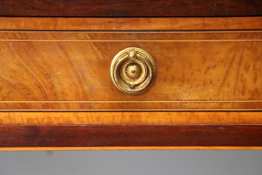 An Edwardian mahogany and satinwood washstand featuring a shaped marble top, wooden splashback, central drawer, and tapered legs on brass castors. View XII