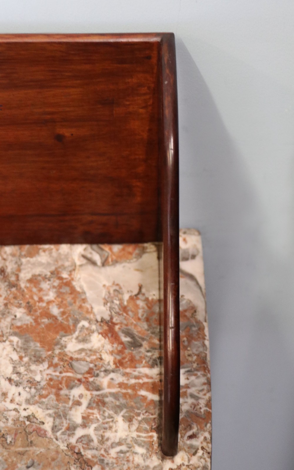 An Edwardian mahogany and satinwood washstand featuring a shaped marble top, wooden splashback, central drawer, and tapered legs on brass castors. View XIV