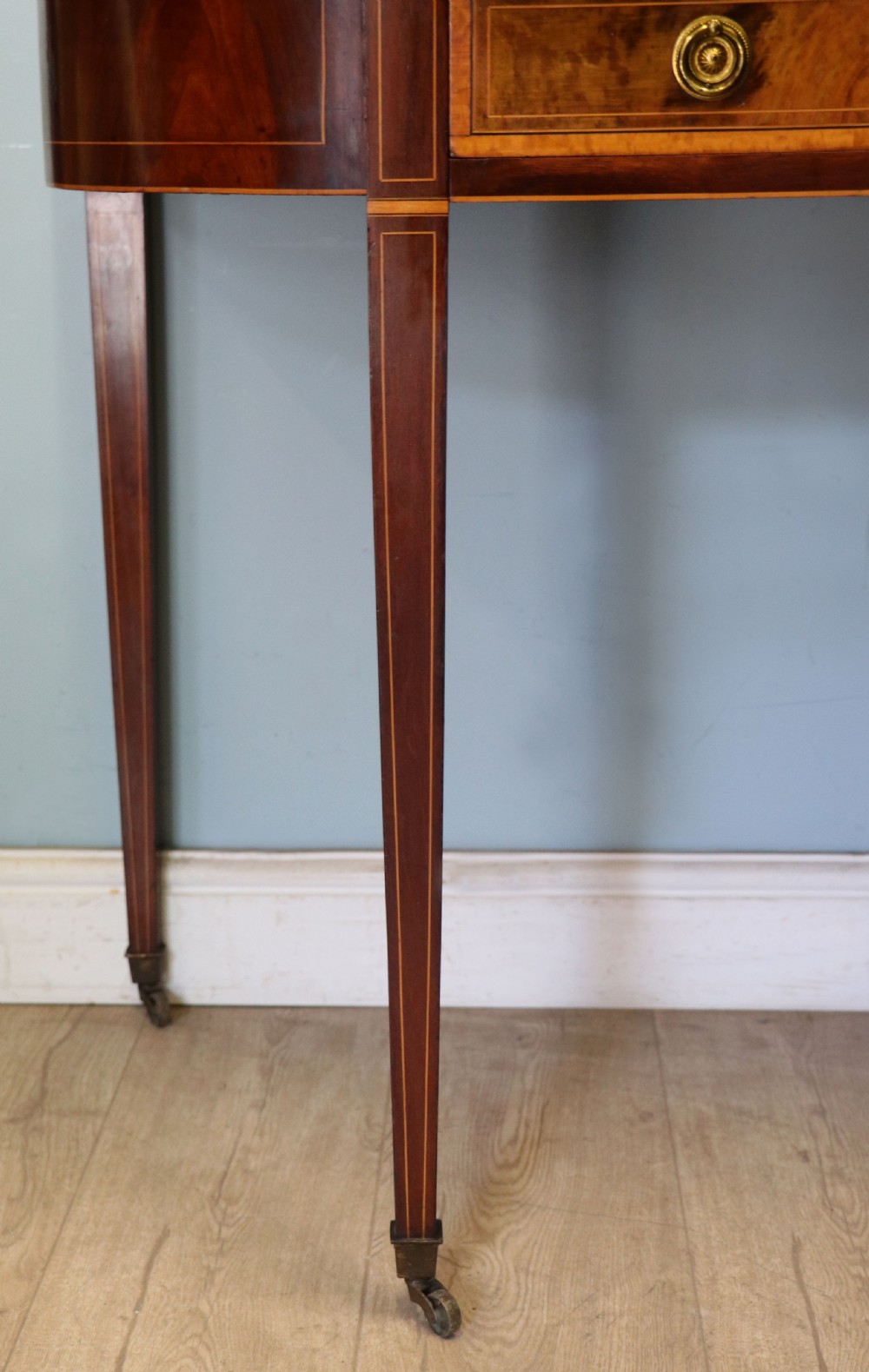 An Edwardian mahogany and satinwood washstand featuring a shaped marble top, wooden splashback, central drawer, and tapered legs on brass castors. View XVII