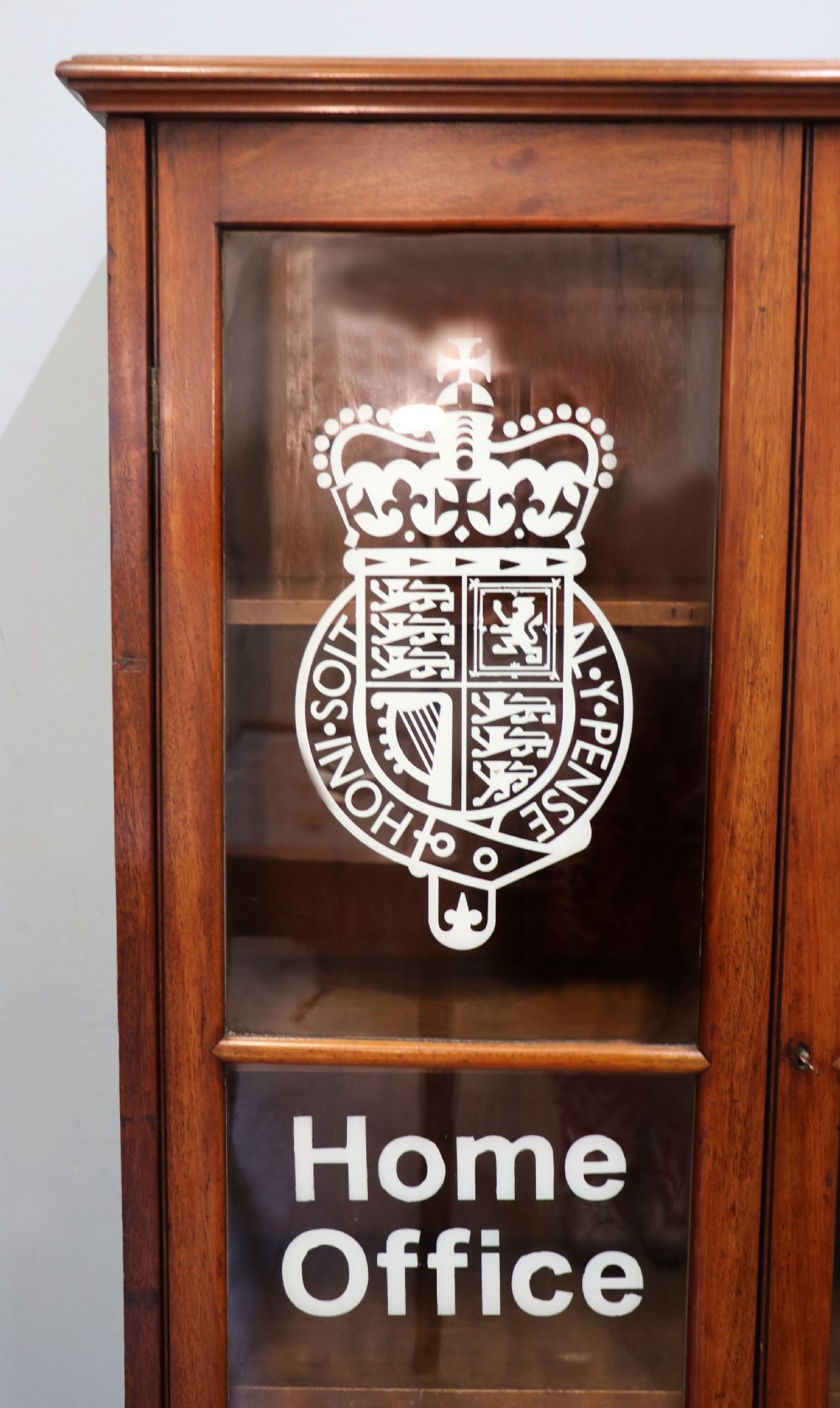 An early twentieth-century mahogany framed bookcase featuring two glazed doors decorated with the Home Office royal coat of arms stencil, supported on cabriole legs. View VII