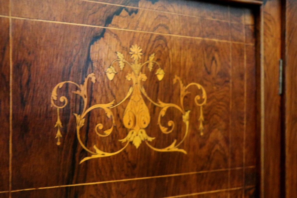 A late nineteenth-century dark hardwood music cabinet featuring floral marquetry inlay on the upper door, an oval mirror panel framed by scroll carving below, and a galleried upper shelf. View XVIII
