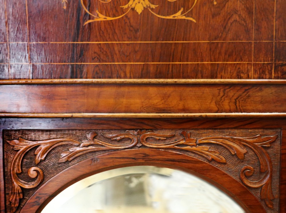 A late nineteenth-century dark hardwood music cabinet featuring floral marquetry inlay on the upper door, an oval mirror panel framed by scroll carving below, and a galleried upper shelf. View XX