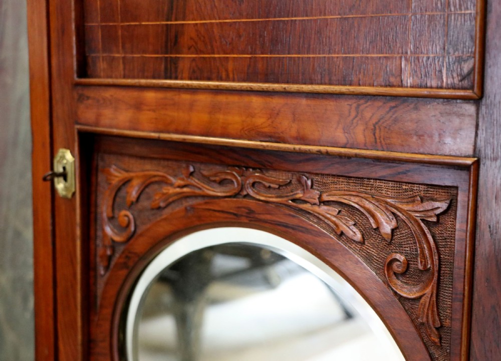 A late nineteenth-century dark hardwood music cabinet featuring floral marquetry inlay on the upper door, an oval mirror panel framed by scroll carving below, and a galleried upper shelf. View XXIII