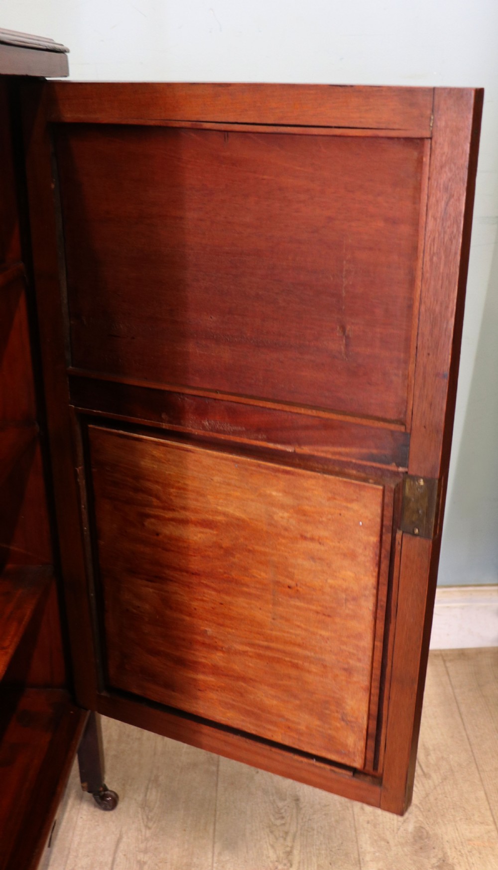 A late nineteenth-century dark hardwood music cabinet featuring floral marquetry inlay on the upper door, an oval mirror panel framed by scroll carving below, and a galleried upper shelf. View XXV