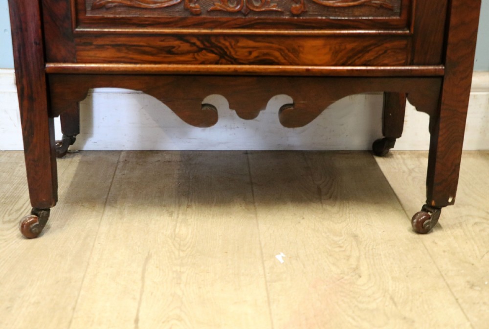 A late nineteenth-century dark hardwood music cabinet featuring floral marquetry inlay on the upper door, an oval mirror panel framed by scroll carving below, and a galleried upper shelf. View XXVI