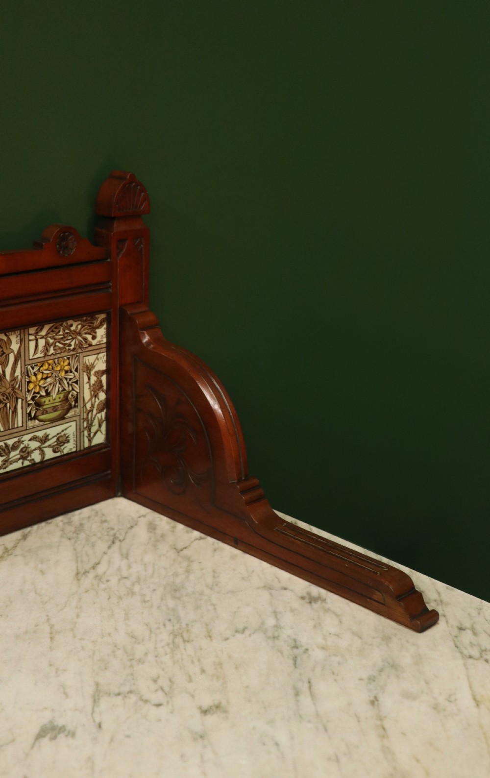 A Victorian Aesthetic Movement mahogany washstand featuring a white marble top, a tiled gallery splashback with floral motifs, two pedestal cupboards, and a central drawer. View XVII