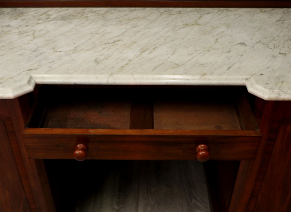 A Victorian Aesthetic Movement mahogany washstand featuring a white marble top, a tiled gallery splashback with floral motifs, two pedestal cupboards, and a central drawer. View XX