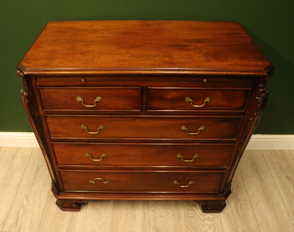 A solid mahogany bachelors chest featuring a pull-out slide, two upper drawers, three lower drawers, brass handles, and carved corner pilasters. View II