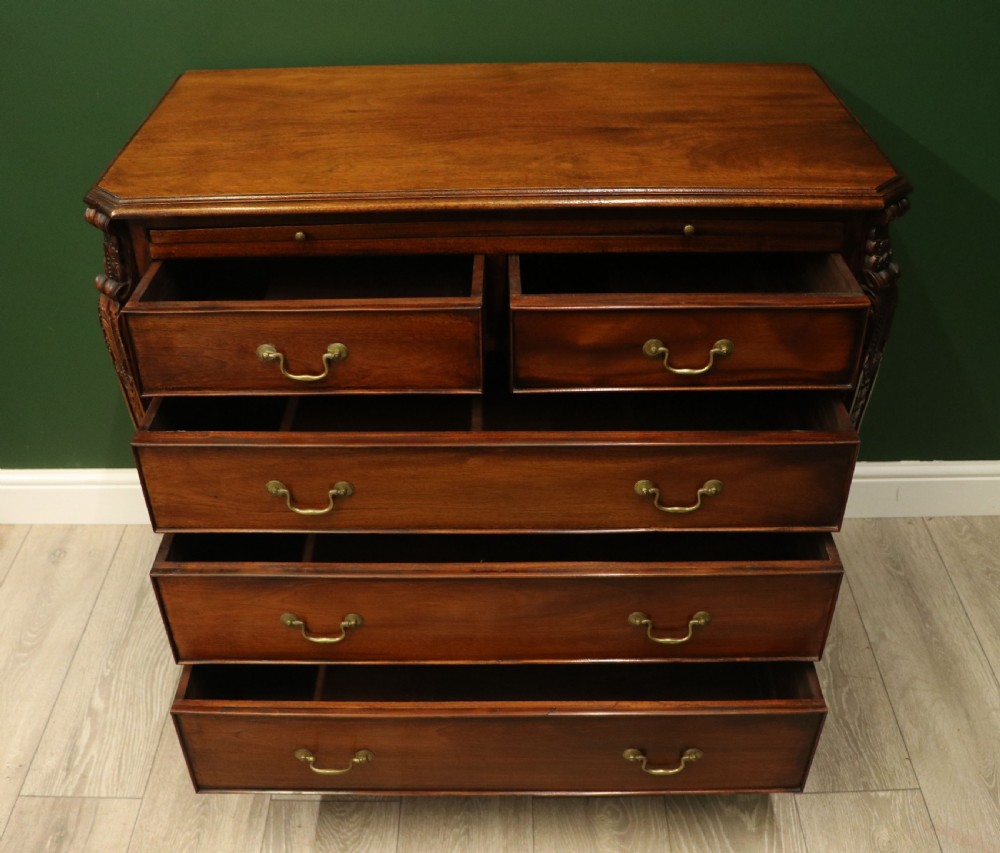 A solid mahogany bachelors chest featuring a pull-out slide, two upper drawers, three lower drawers, brass handles, and carved corner pilasters. View III