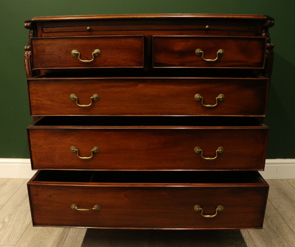 A solid mahogany bachelors chest featuring a pull-out slide, two upper drawers, three lower drawers, brass handles, and carved corner pilasters. View IV