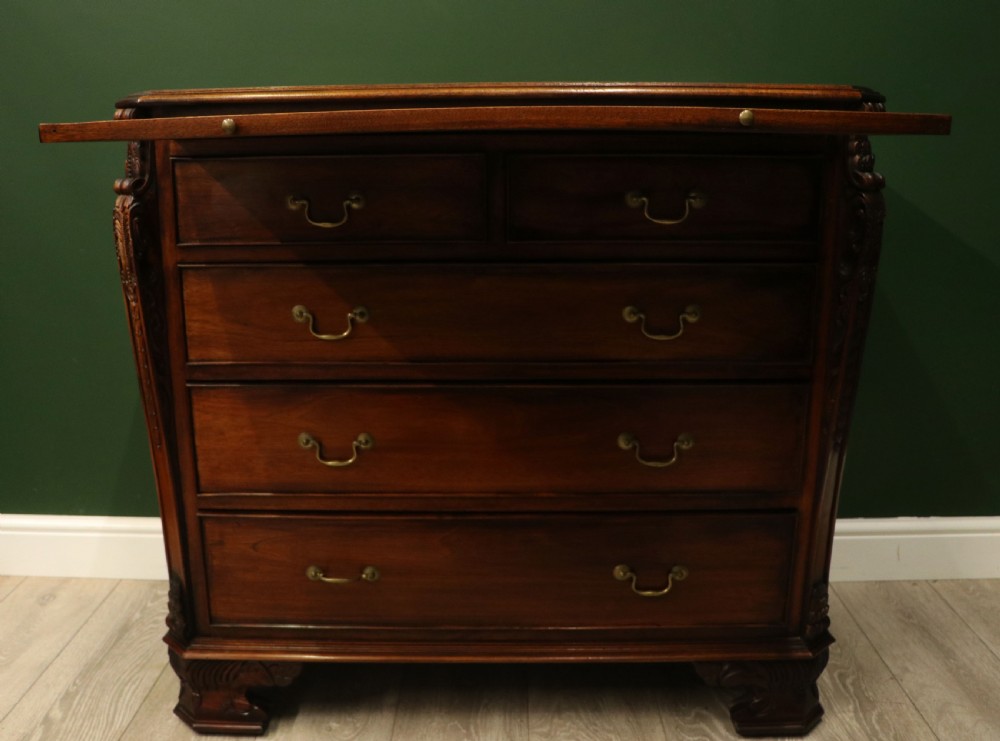 A solid mahogany bachelors chest featuring a pull-out slide, two upper drawers, three lower drawers, brass handles, and carved corner pilasters. View VI