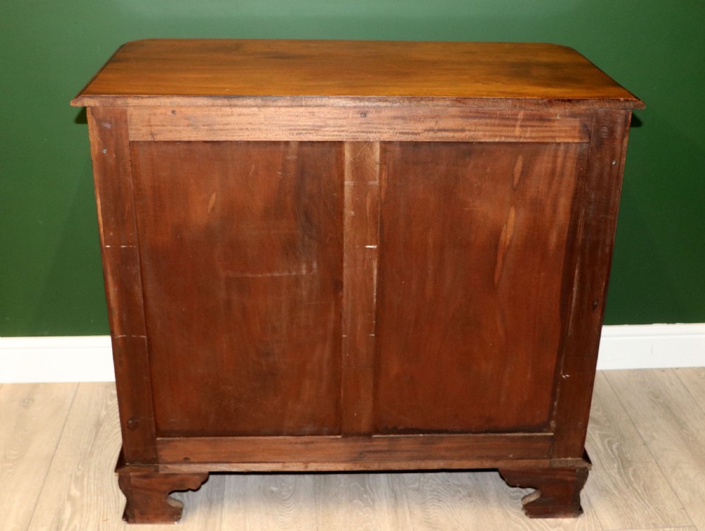 A solid mahogany bachelors chest featuring a pull-out slide, two upper drawers, three lower drawers, brass handles, and carved corner pilasters. View X