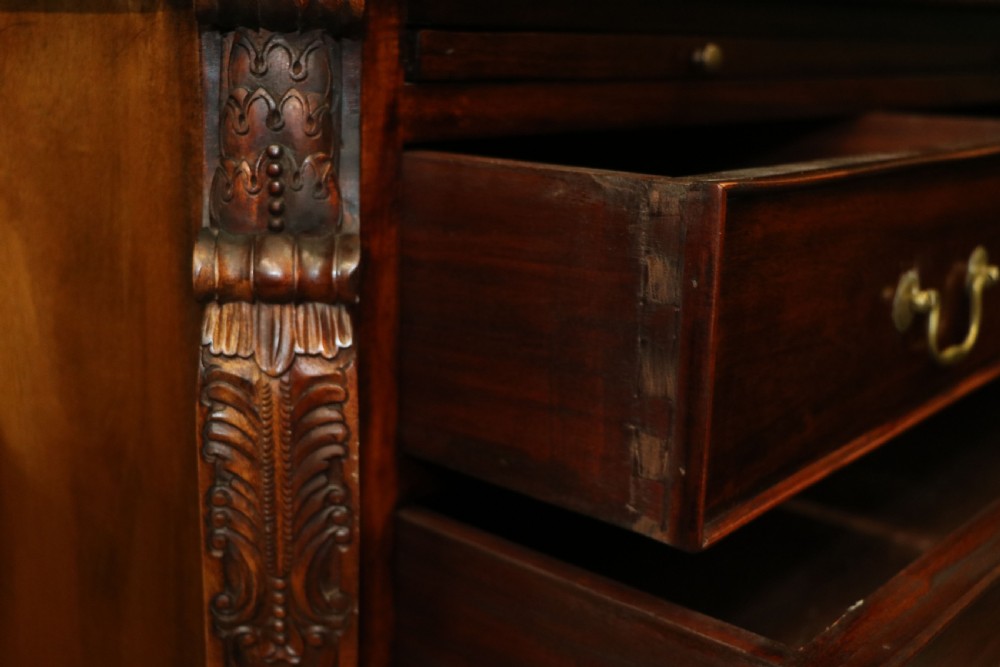 A solid mahogany bachelors chest featuring a pull-out slide, two upper drawers, three lower drawers, brass handles, and carved corner pilasters. View XIX