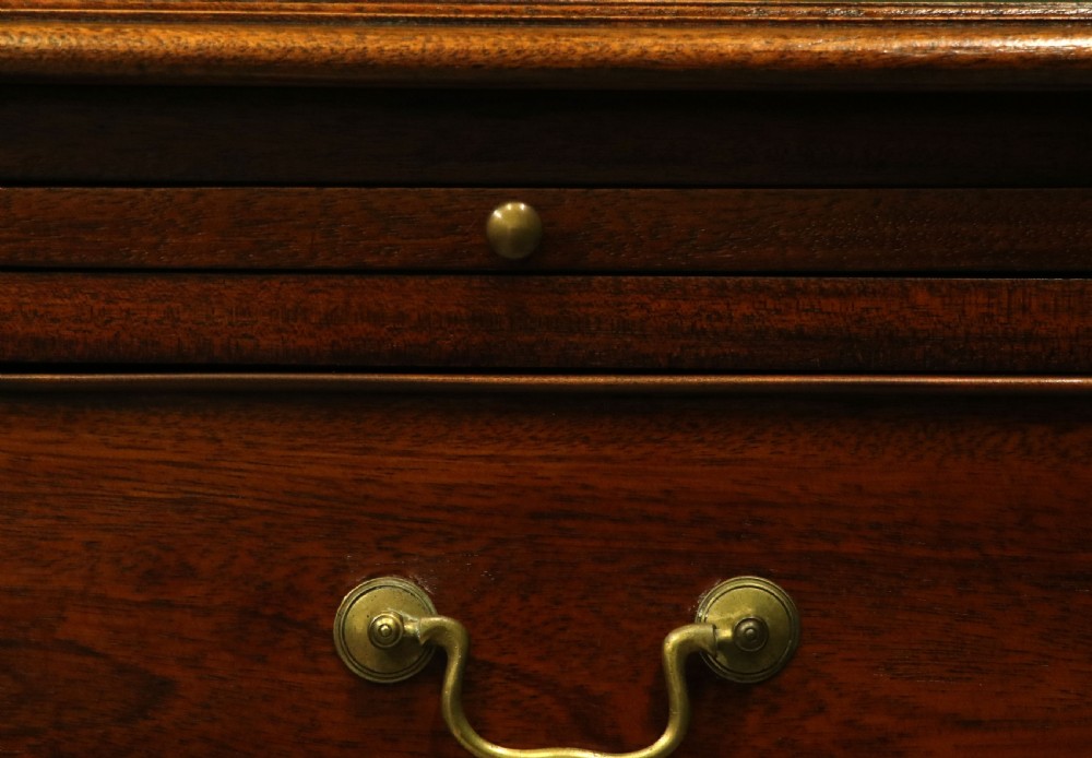 A solid mahogany bachelors chest featuring a pull-out slide, two upper drawers, three lower drawers, brass handles, and carved corner pilasters. View XXII