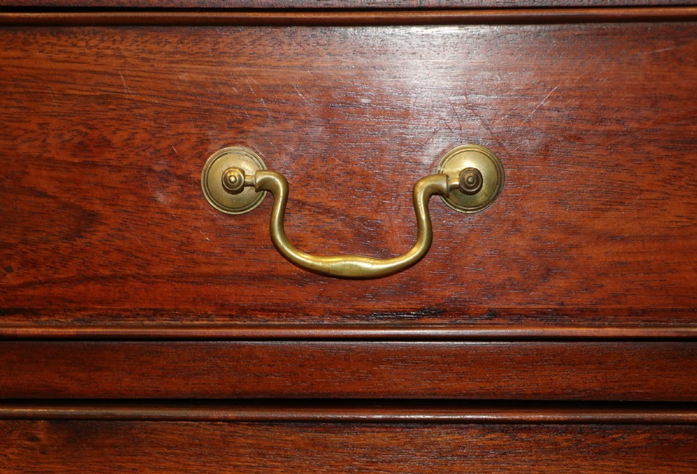 A solid mahogany bachelors chest featuring a pull-out slide, two upper drawers, three lower drawers, brass handles, and carved corner pilasters. View XXIII