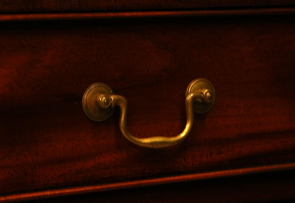 A solid mahogany bachelors chest featuring a pull-out slide, two upper drawers, three lower drawers, brass handles, and carved corner pilasters. View XXIV