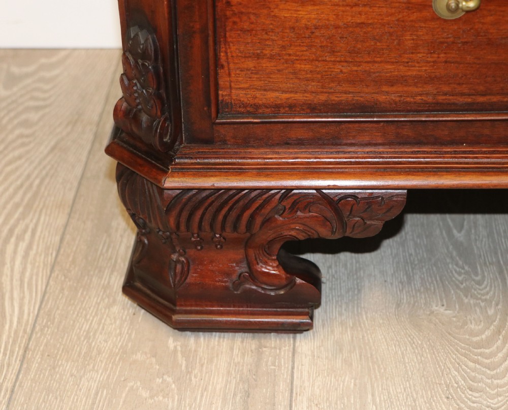 A solid mahogany bachelors chest featuring a pull-out slide, two upper drawers, three lower drawers, brass handles, and carved corner pilasters. View XXV