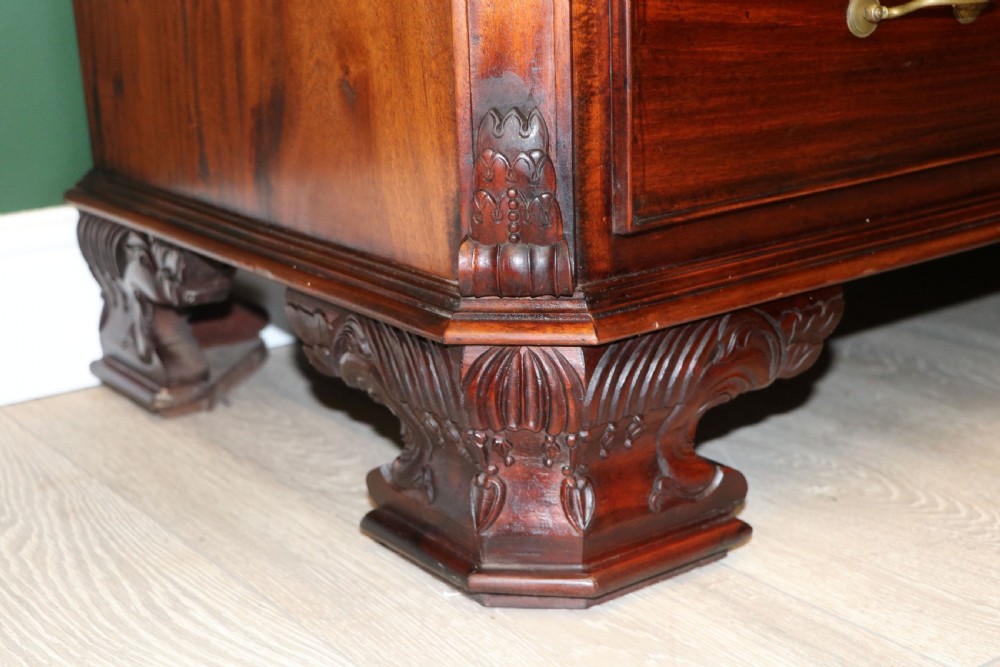 A solid mahogany bachelors chest featuring a pull-out slide, two upper drawers, three lower drawers, brass handles, and carved corner pilasters. View XXVII