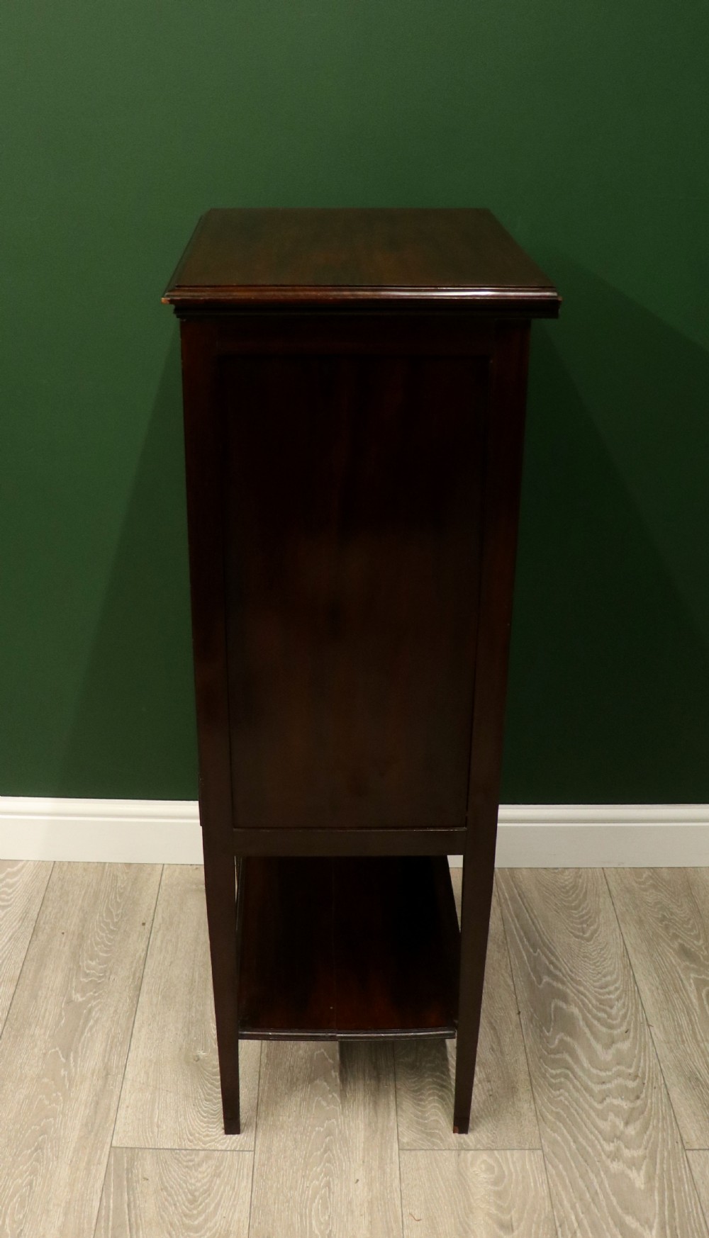 A tall, narrow dark mahogany music cabinet featuring seven fall-front drawers with central brass ring handles and an open shelf near the base. View XIII