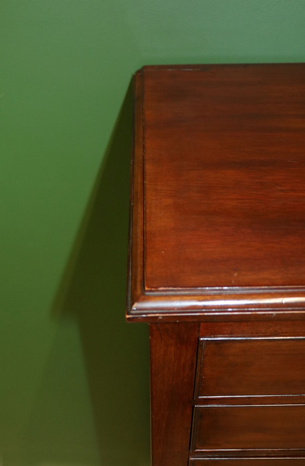 A tall, narrow dark mahogany music cabinet featuring seven fall-front drawers with central brass ring handles and an open shelf near the base. View XV
