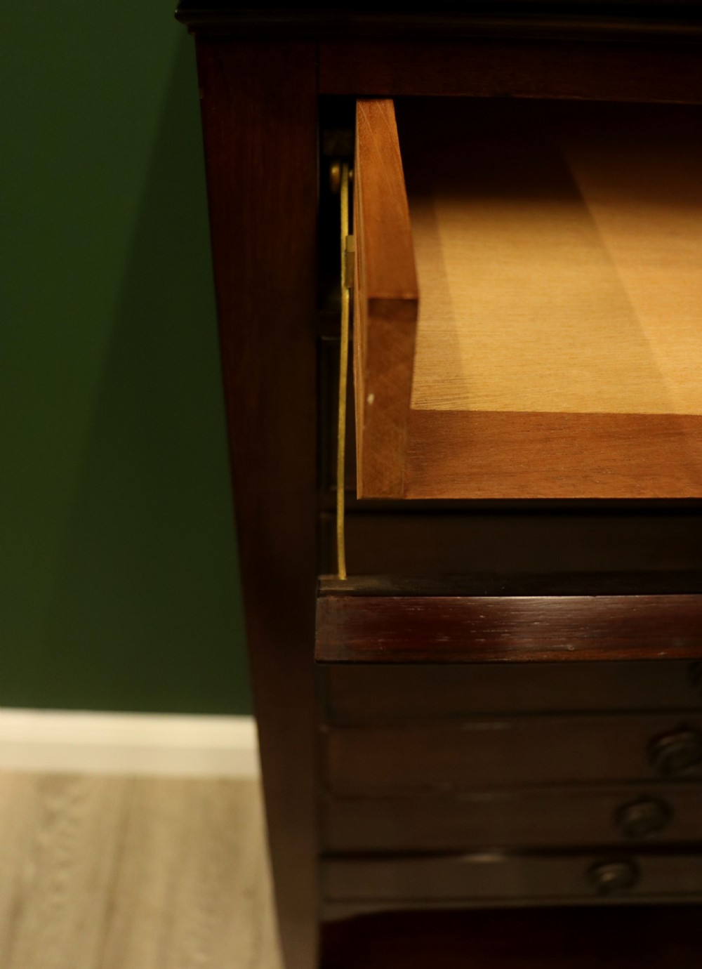 A tall, narrow dark mahogany music cabinet featuring seven fall-front drawers with central brass ring handles and an open shelf near the base. View XVII