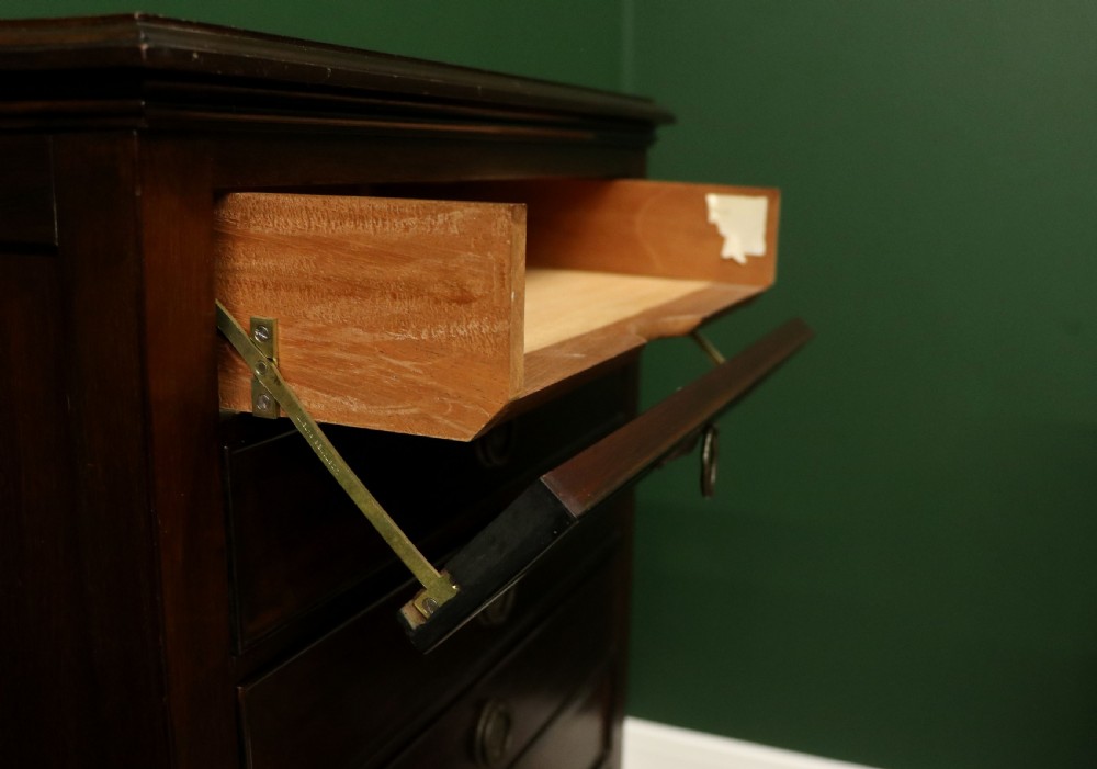 A tall, narrow dark mahogany music cabinet featuring seven fall-front drawers with central brass ring handles and an open shelf near the base. View XVIII