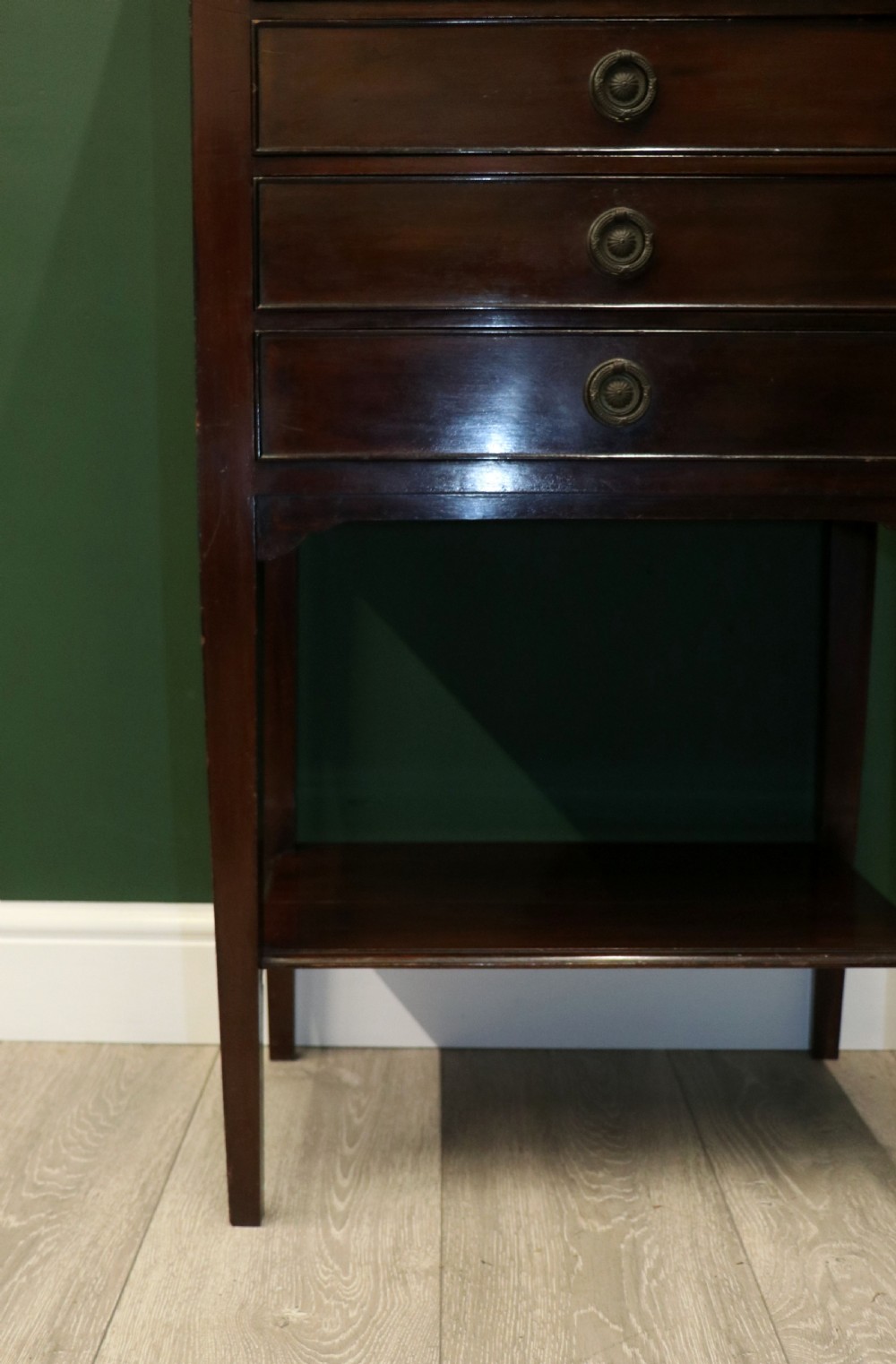 A tall, narrow dark mahogany music cabinet featuring seven fall-front drawers with central brass ring handles and an open shelf near the base. View XIX