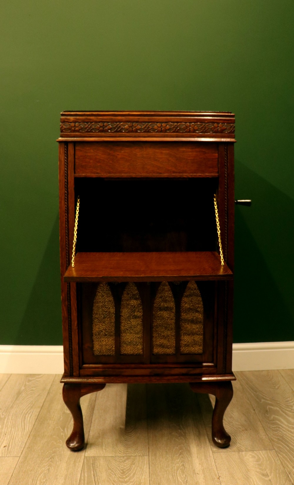 An upright dark oak parlour gramophone cabinet featuring cabriole legs, a hinged lid, carved rope detailing, and gothic arch fretwork grilles. View III