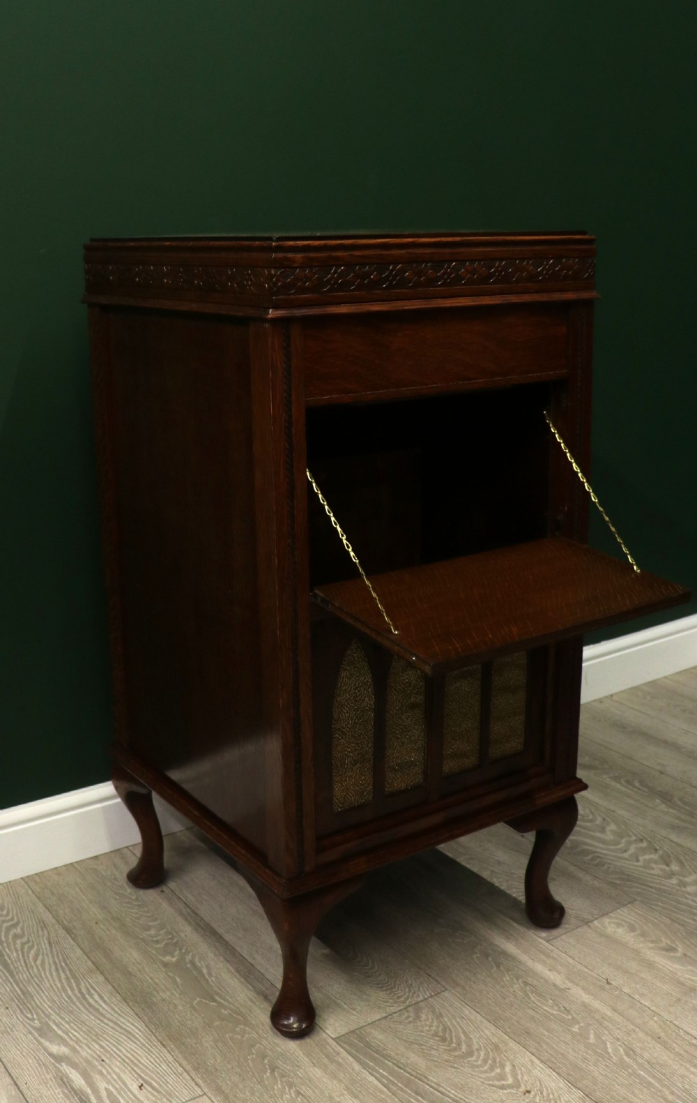 An upright dark oak parlour gramophone cabinet featuring cabriole legs, a hinged lid, carved rope detailing, and gothic arch fretwork grilles. View VIII