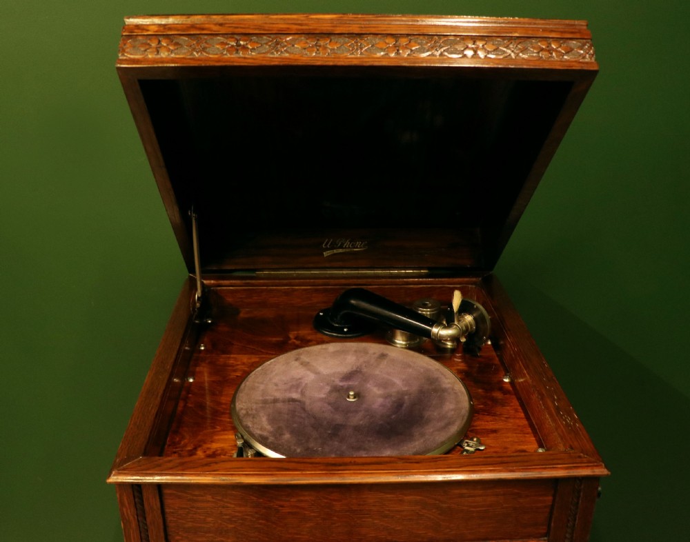 An upright dark oak parlour gramophone cabinet featuring cabriole legs, a hinged lid, carved rope detailing, and gothic arch fretwork grilles. View XV
