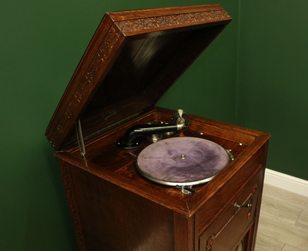 An upright dark oak parlour gramophone cabinet featuring cabriole legs, a hinged lid, carved rope detailing, and gothic arch fretwork grilles. View XVI