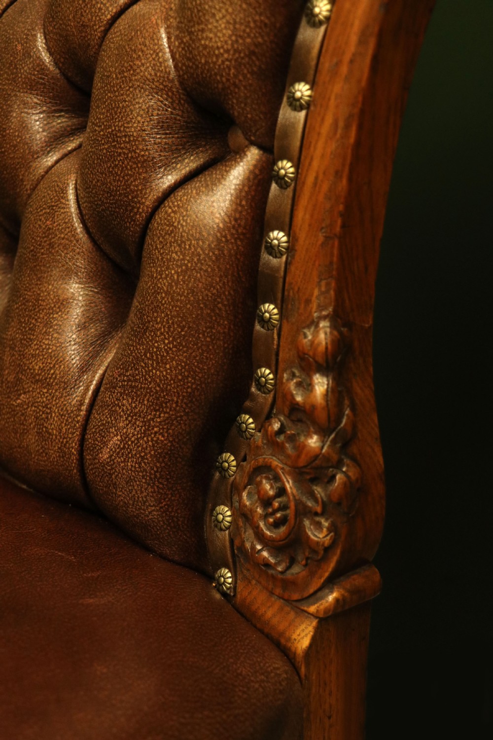 A pair of Victorian carved oak side chairs upholstered in deep-buttoned brown leather with brass studding and turned front legs on castors. View XVI