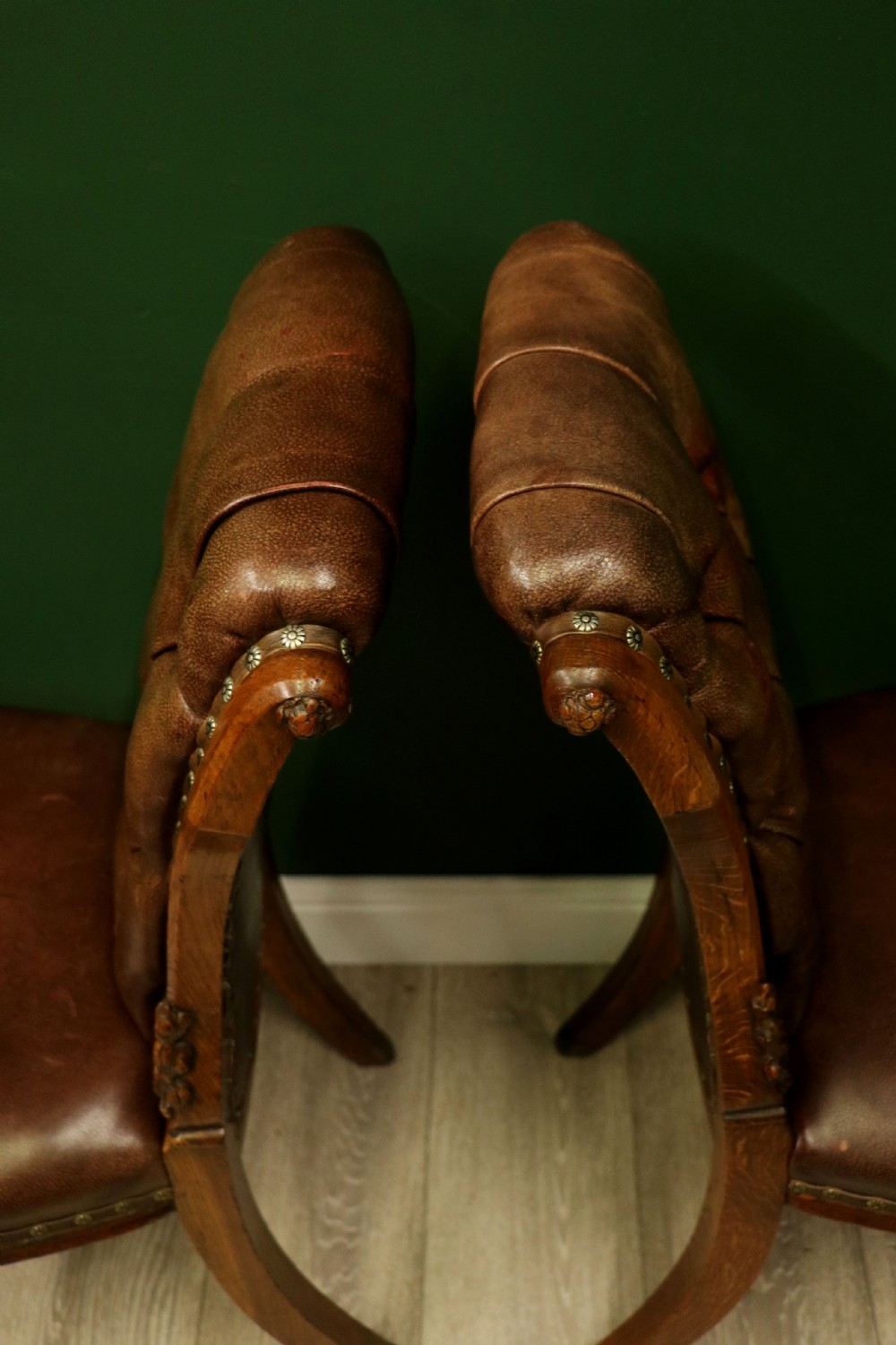 A pair of Victorian carved oak side chairs upholstered in deep-buttoned brown leather with brass studding and turned front legs on castors. View XVII