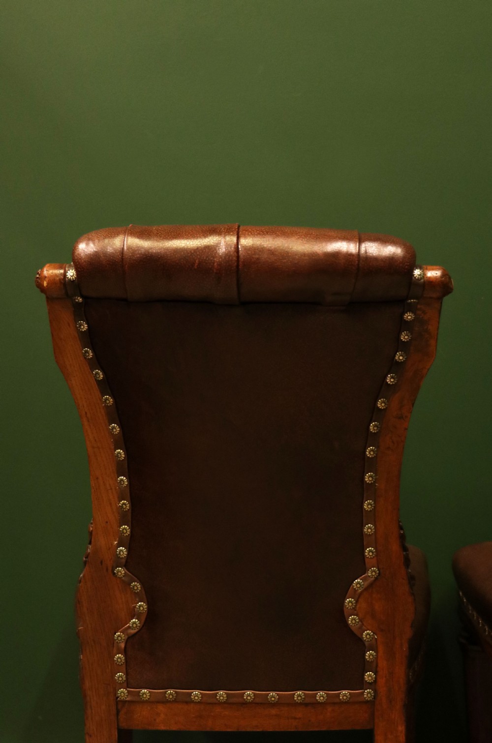 A pair of Victorian carved oak side chairs upholstered in deep-buttoned brown leather with brass studding and turned front legs on castors. View XVIII