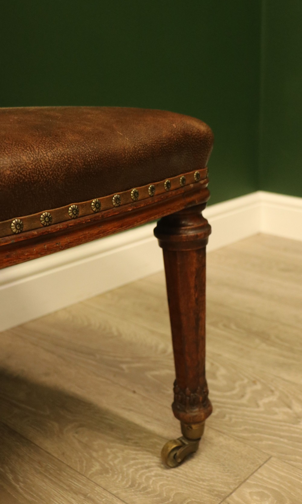 A pair of Victorian carved oak side chairs upholstered in deep-buttoned brown leather with brass studding and turned front legs on castors. View XXIII