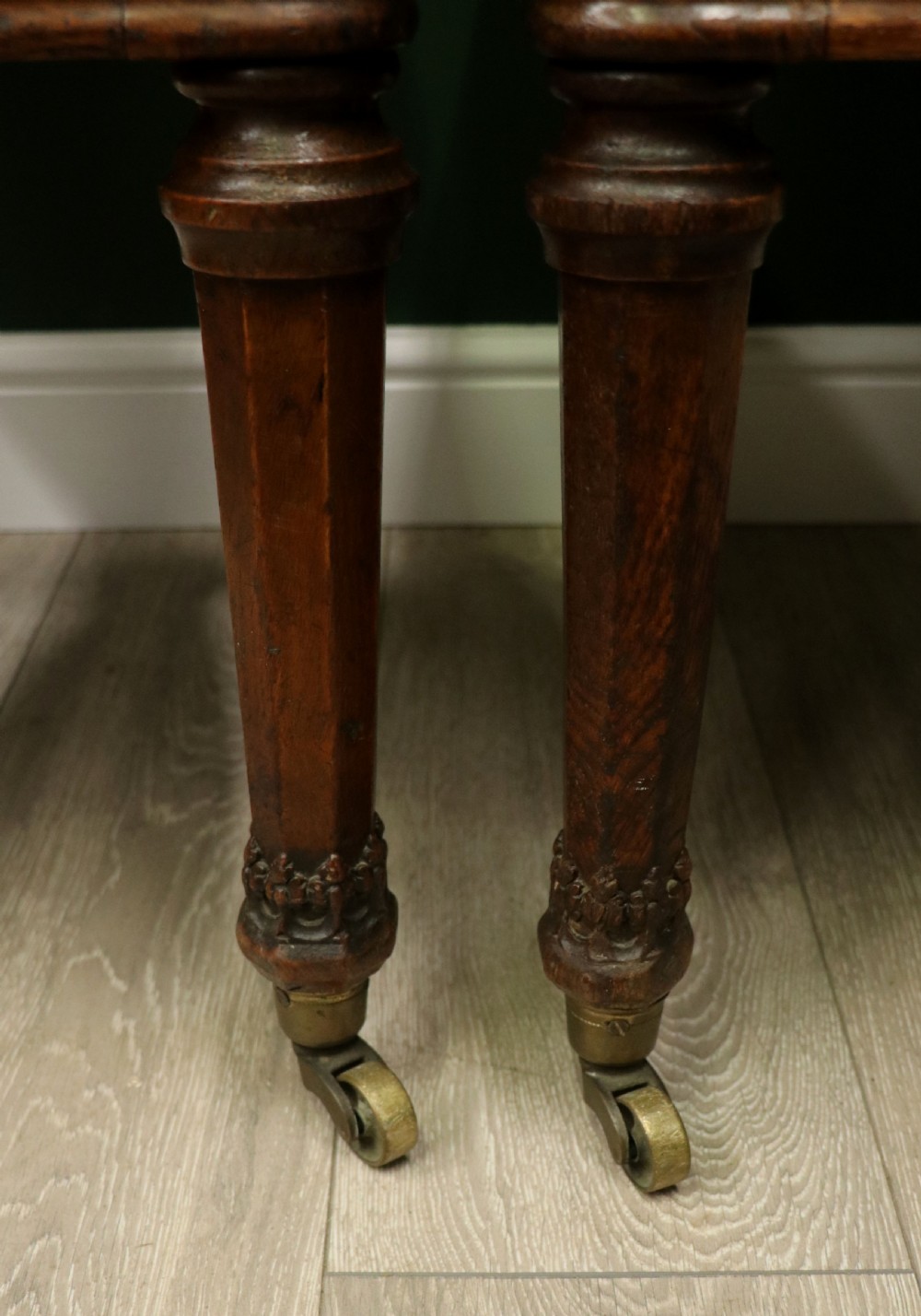 A pair of Victorian carved oak side chairs upholstered in deep-buttoned brown leather with brass studding and turned front legs on castors. View XXIV
