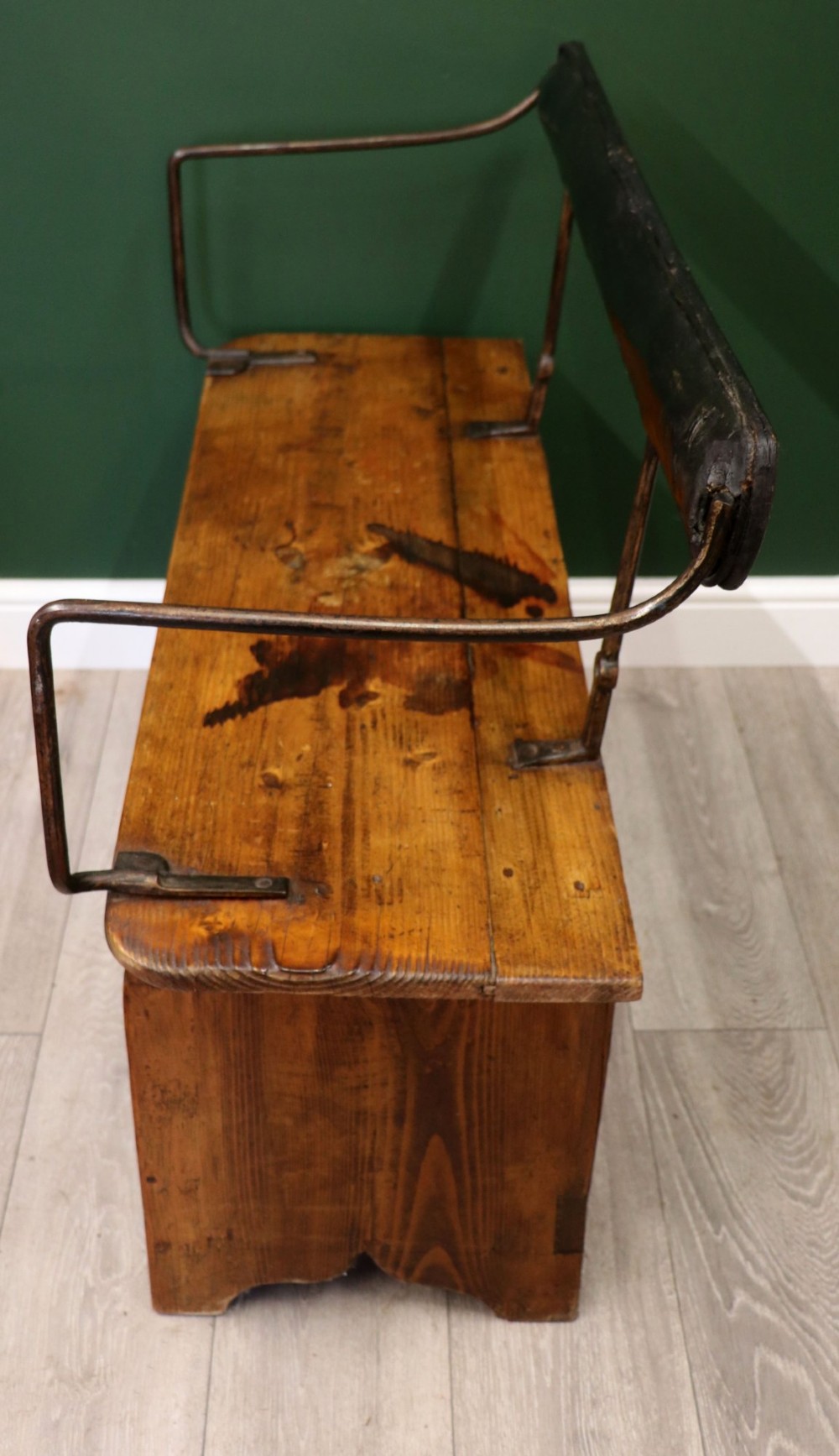 An antique pine wooden bench featuring a shaped aproned base, integrated lower shelf, wrought iron armrests, and a black leather padded cylindrical bolster backrest. View VIII