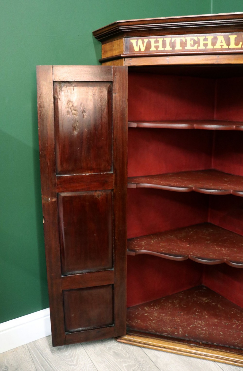 A George III mahogany wall-mounted corner cabinet with double panelled doors featuring painted yellow Roman numerals and a top frieze reading WHITEHALL 1212. View XIII