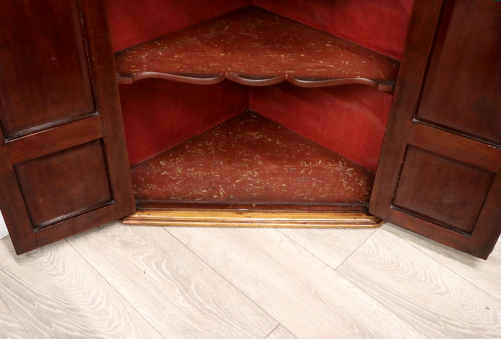 A George III mahogany wall-mounted corner cabinet with double panelled doors featuring painted yellow Roman numerals and a top frieze reading WHITEHALL 1212. View XV