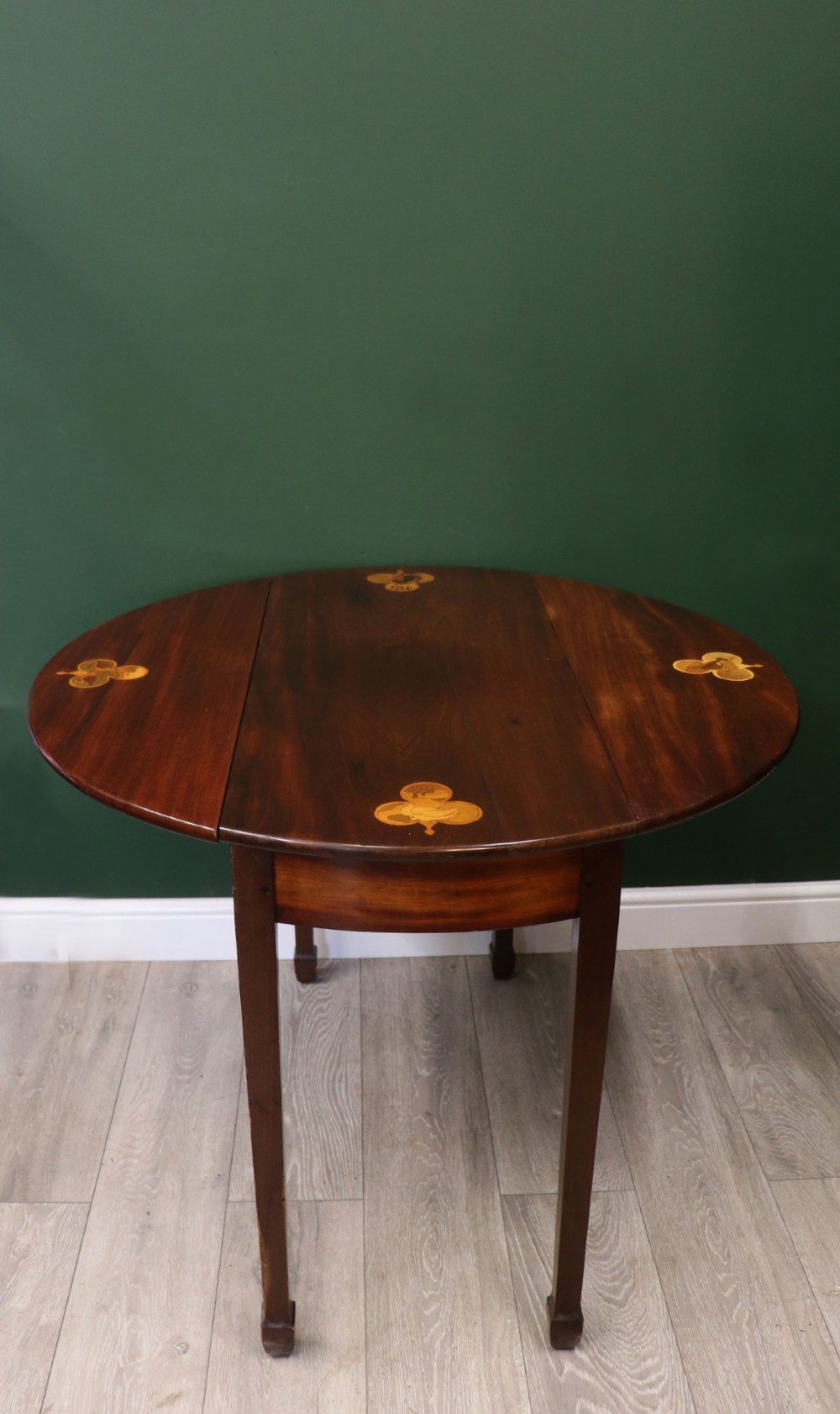 An Edwardian mahogany oval Pembroke table featuring drop leaves and inlaid clover motifs on tapered legs.