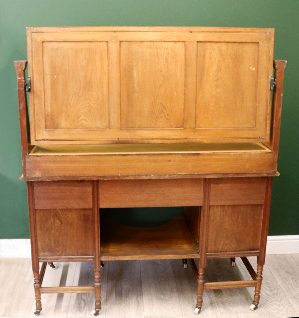 A late Victorian light walnut dressing table featuring an attached rectangular mirror, three small upper drawers, two panelled side cupboards, and turned legs with castors. View V